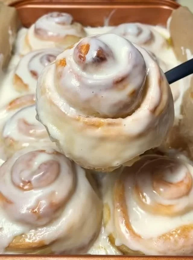 Freshly baked cinnamon rolls with icing on a plate