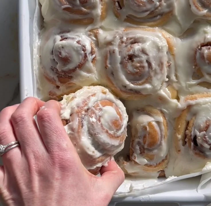 Delicious homemade cinnamon rolls topped with icing on a wooden table.