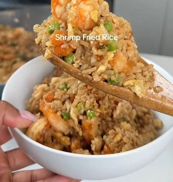 Shrimp fried rice dish garnished with yum yum sauce and vegetables