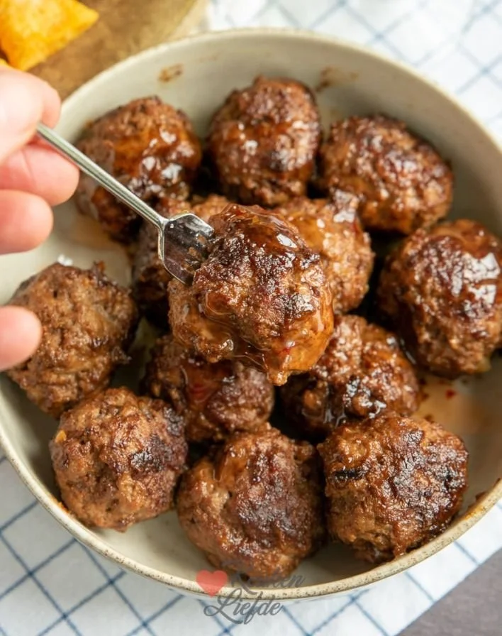 Plate of spicy meatballs in sweet ketjap chili sauce with garnishes