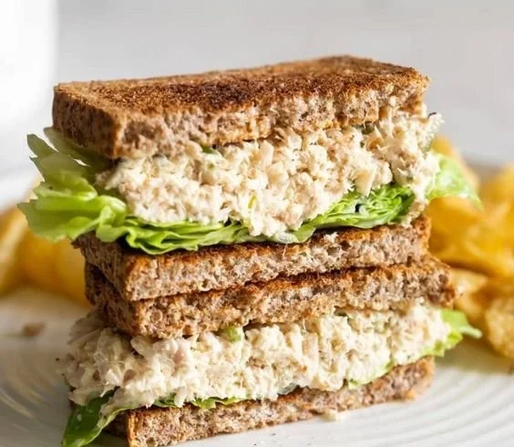 Delicious tuna salad sandwich with mayo and pickles on a plate
