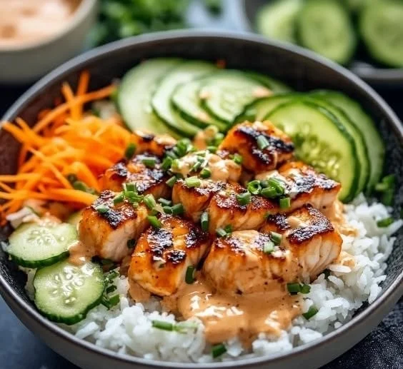 Delicious Bang Bang Salmon Bowls topped with spicy sauce and fresh vegetables