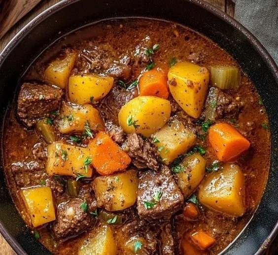 Classic beef stew simmering in a pot with vegetables and herbs.