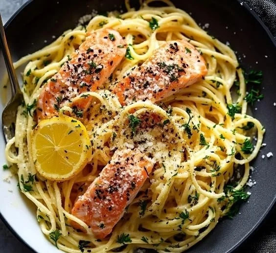 Creamy salmon pasta dish with fresh herbs and lemon garnish