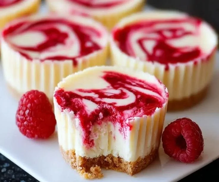 Delicious mini raspberry swirl cheesecakes served on a plate.