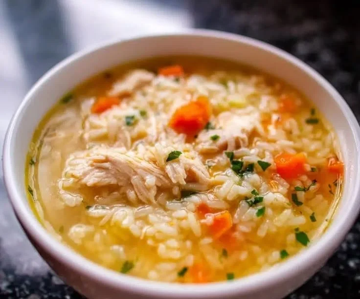 Bowl of One-Pot Cozy Chicken Rice Soup with herbs and vegetables