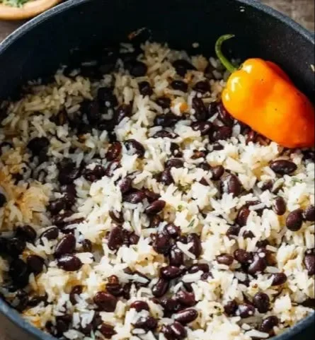 Bowl of Caribbean Coconut Milk Rice and Beans garnished with herbs.