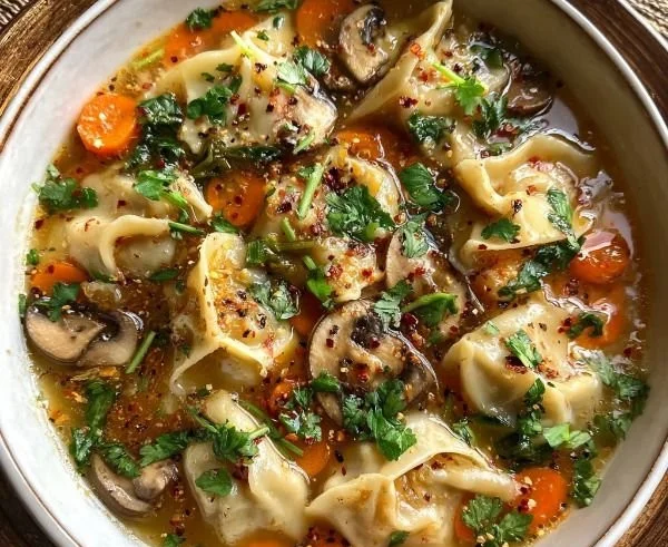 Delicious bowl of cozy potsticker soup topped with fresh herbs and vegetables.